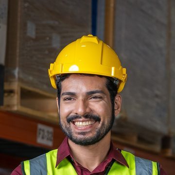 Smiling warehouse worker in a yellow hard hat and hi-vis vest